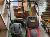 two lawn mowers sitting on the floor next to each other