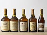 six bottles of wine are lined up on a wooden table