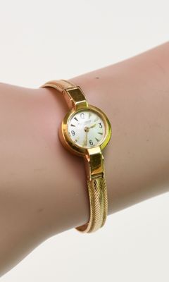Quelqu'un porte une montre-bracelet en or avec un cadran blanc.