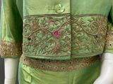 an image of a mannequin wearing a green dress with a pink button