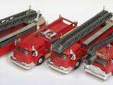 quatre camions de pompiers rouges alignés sur une surface blanche