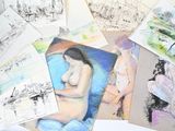 une pile de dessins posée sur une table recouverte de feuilles de papier