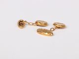 a close up of a pair of gold earrings on a white surface