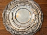 une assiette en argent posée sur une table en bois, à côté d'autres assiettes