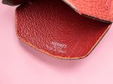 a close up of a red leather wallet on a pink surface