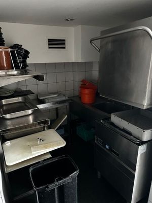une petite cuisine équipée d'une cuisinière, d'un évier et d'une poubelle