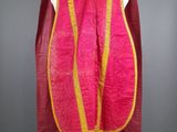 une robe rose et jaune avec une cape rouge sur un mannequin