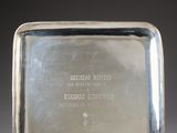 an antique silver plate with a metal handle on a metal stand