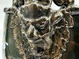 a close up of a vase with a ram head on it