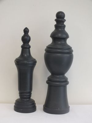 deux vases noirs posés sur une table blanche, avec une horloge en arrière-plan