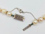 pearl necklace with a silver clasp and a key on a white background