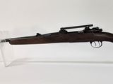 Le fusil est exposé sur un socle en acrylique transparent.