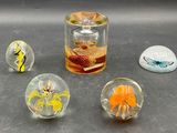 four glass marbles sitting on a table next to a glass jar