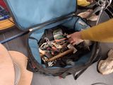 a person opening a suitcase on the floor with a lot of things in it