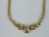 a gold necklace with three diamonds on a chain
