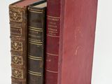 two old books sitting on top of each other on a white surface