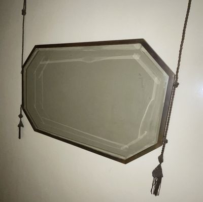 a mirror hanging on the wall with a rope