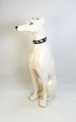 un chien blanc avec un collier, assis sur une surface blanche