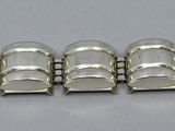 five silver bracelets that are on a white surface
