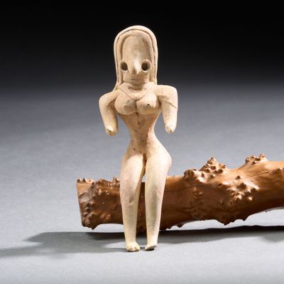 figurine représentant une femme debout sur une branche d'arbre, les mains sur les hanches