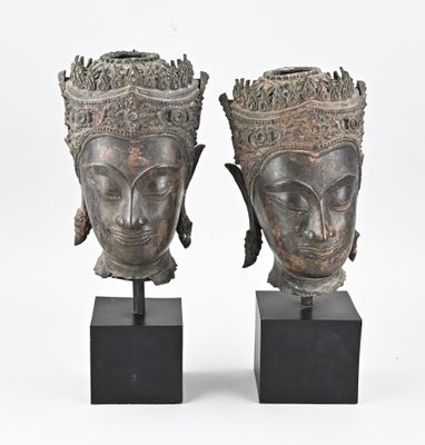 paire de vases en forme de tête en bronze posés sur des socles noirs, sur fond blanc