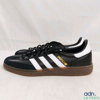 Les baskets adidas sont noires et blanches, avec une semelle marron.