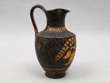 an old black and gold vase sitting on top of a white surface