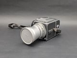 a silver camera with a white lens on a gray surface