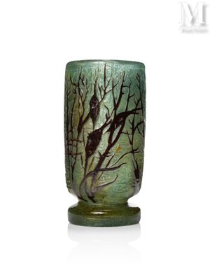 un vase vert orné d'oiseaux, posé sur une table