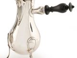 une cafetière ancienne en argent avec une poignée noire sur fond blanc