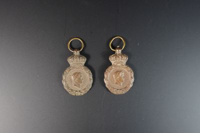 deux boucles d'oreilles en or ornées d'un médaillon, posées sur une surface noire