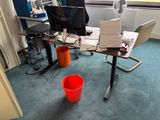 un seau rouge posé devant un bureau sur lequel se trouve un ordinateur