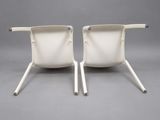 two white chairs with metal legs on a gray background