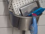 a metal sink with a bucket of cleaning supplies inside of it