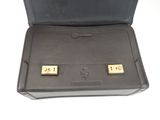 black leather briefcase with two gold - plated cufflinks in it