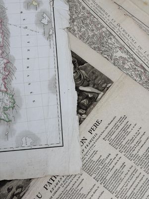de nombreuses cartes anciennes posées sur une table recouverte de papiers