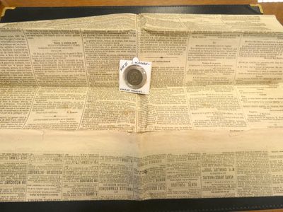 un livre ouvert, sur lequel repose une pièce de monnaie, posé sur une table