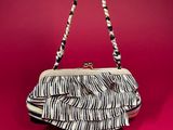 a woman ' s hand holding a zebra print purse on a red background