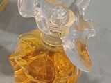a glass bottle with a flower on it next to a bottle of perfume