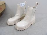 pair of white leather boots sitting on top of a gray floor