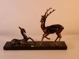 statue en bronze représentant un cerf et un homme, posée sur un socle en bois