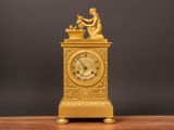 a gold clock sitting on a wooden table with a black background