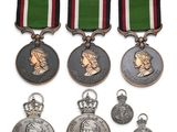 trois médailles et une médaille sont exposées sur un support blanc