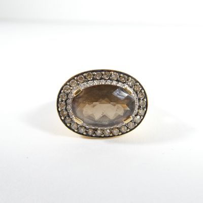 un gros plan d'une bague ornée d'une pierre brune entourée de diamants