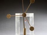 une image représentant une sculpture en métal et en verre, avec une boule rouge au centre