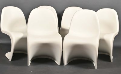 quatre chaises en plastique blanc disposées les unes à côté des autres sur une surface noire