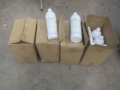 quatre cartons contenant différents types de produits d'entretien, posés par terre