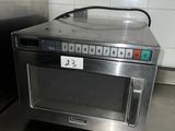 a silver microwave sitting on a metal counter in a kitchen