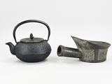 two teapots and a watering can sitting next to each other