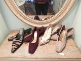 a woman taking a selfie in front of a mirror with several pairs of shoes on a table